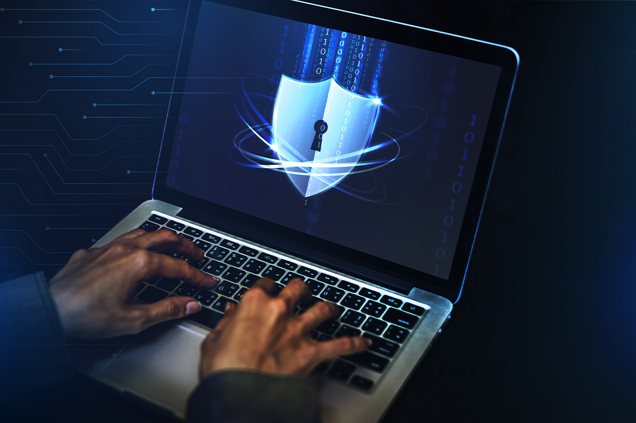 Laptop mit digitalem Sicherheitsschild und Händen, die auf der Tastatur tippen.